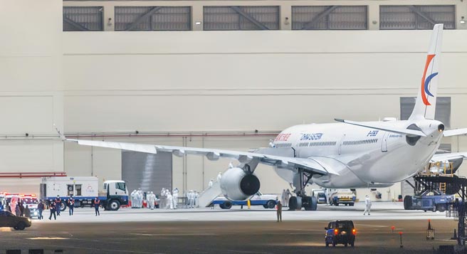 2020年2月3日，东航载送的台商首班武汉返台包机飞抵桃园机场。专案小组全副武装在飞机维修公司厂棚为旅客办理检疫消毒与入关程序。（本报系资料照片）