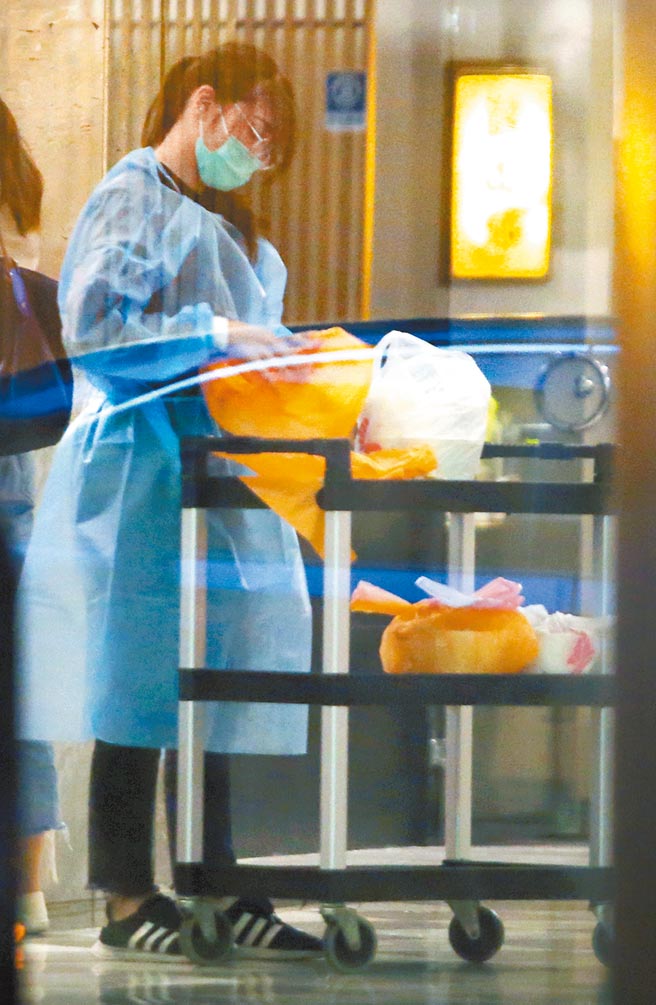 全台防疫旅館因歸國返鄉人潮爆滿，讓還在國外的民眾面臨無房可訂的窘境，在1家防疫旅館中，身穿防護衣的工作人員正準備房客的餐點。（范揚光攝）