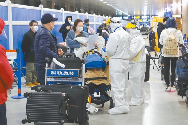防範病毒偷渡入境，2020年12月31日晚，上海浦東機場工作人員全副武裝再三對旅客進行信息核查。（中新社）