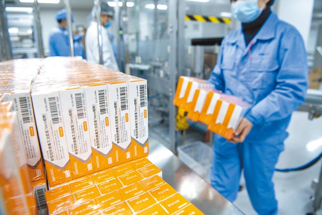 1月6日，工人搬运整理包装流水线上的预充式注射器装疫苗。（中新社）