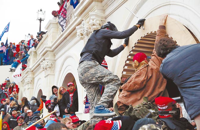 川粉攀上围墙门缝，强攻国会山庄。（路透）