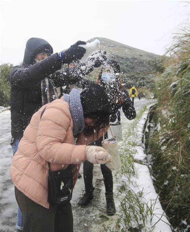 全台急冻，大台北地区大屯山持续飘下细雪，许多民眾纷纷穿上冬衣衝上山赏雪，在登山步道上与朋友打雪仗。（张铠乙摄）