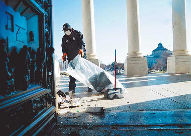 川普总统的支持者大闹国会大厦之后次日，清洁人员展开清扫工作。图为一名清洁人员在国会大厦外清理碎片。（路透）