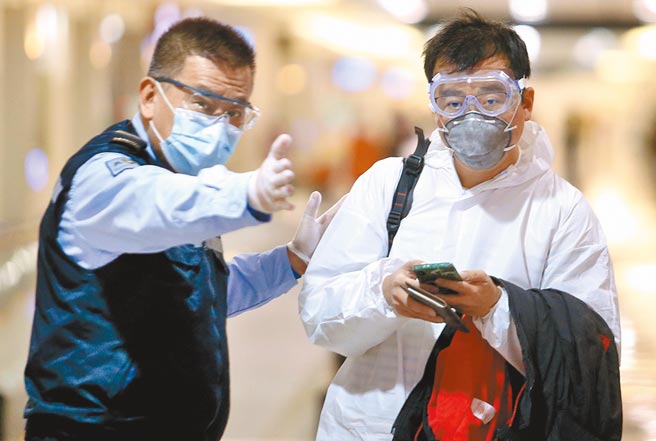 在桃园机场入境管制区内，身穿防护衣的旅客在防疫人员引导下，准备通关入境。（范扬光摄）