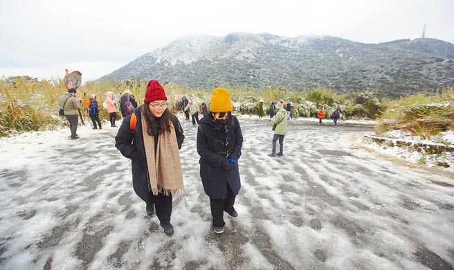 全台急冻，大屯山持续飘下细雪，许多民眾纷纷穿上冬衣衝上山赏雪，并在登山步道与朋友打雪仗。（张铠乙摄）
