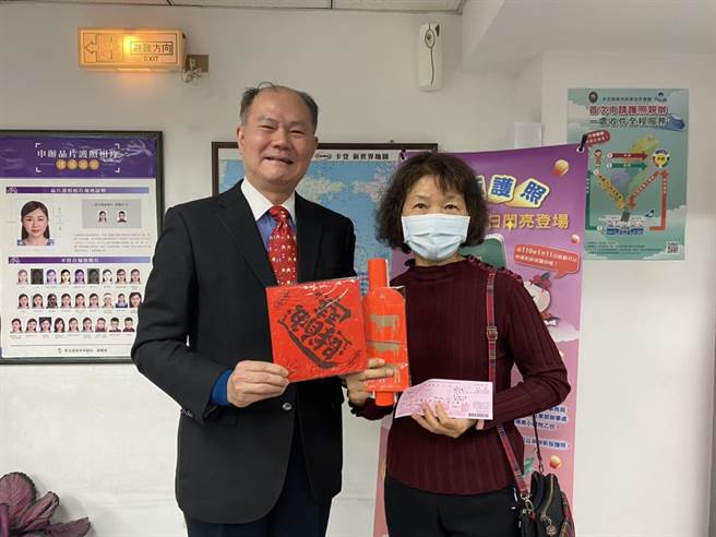 花蓮許多民眾今天一早就拿著舊護照前往外交部東部辦事處更換，外交部東部辦事處長粘信士（左）也將小禮品贈與蕭姓民眾（右）。（羅亦晽攝）