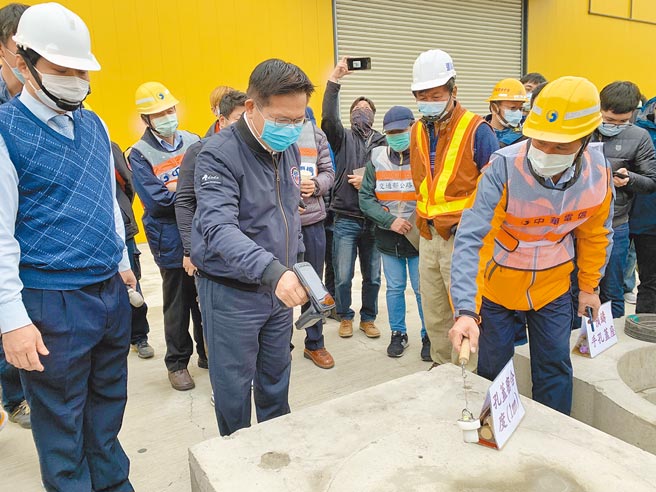 交通部长林佳龙（左二）视察「微创施工孔盖启闭创新工法」，特别拿起机器确认孔盖位置及其管线单位等资讯。（林欣仪摄）
