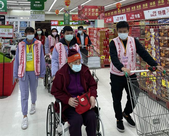 石冈国中14位学生推着坐轮椅的独居长辈逛卖场採买。（王文吉摄）