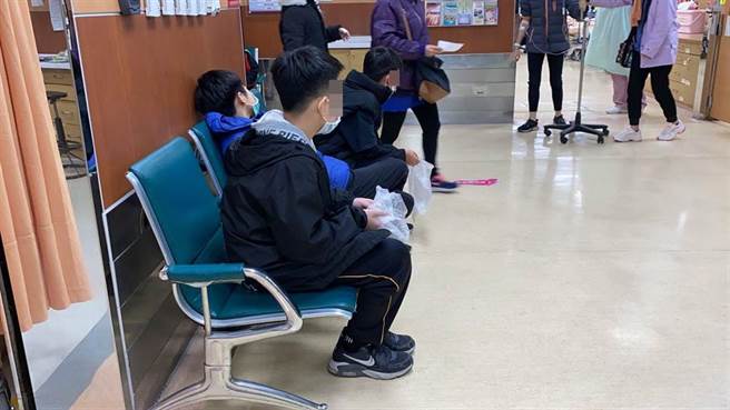 身體不適的學童坐在急診室，對著塑膠袋嘔吐，臉色發白，顯得虛弱。（廖素慧攝）