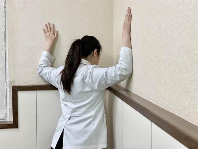 物理治疗师林惠玲示范第二招【扩胸运动】：站立姿，双手放头后方，挺胸、双手往后牵拉，每下维持15秒，做15下。（柯宗纬摄）