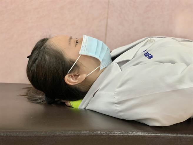 物理治疗师林惠玲示范第三招【按摩枕骨下肌】：平躺，将小球置于枕骨下肌位置，可用手协助固定小球，给予压迫，维持30秒。此区域较敏感，使用轻的力道至感觉微酸、微紧即可。（柯宗纬摄）