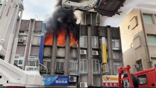 花莲市中正路一间钟表行今早发生火灾，火舌不时从窗口冒出。（民眾提供／罗亦晽花莲传真）