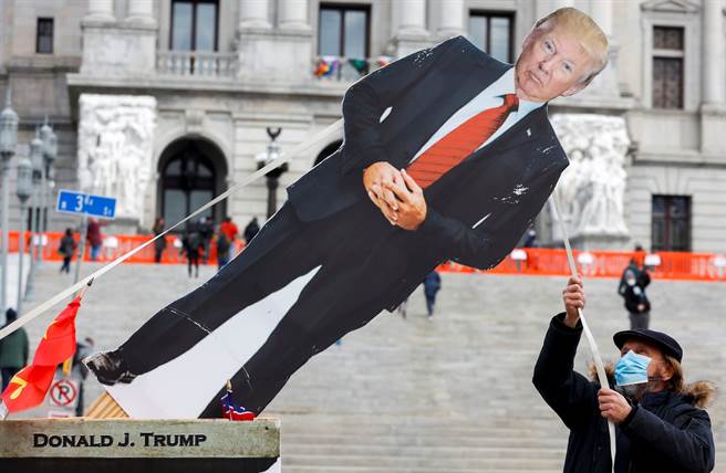 一名反川人士1月17日在宾州首府哈立斯堡（Harrisburg）拉倒美国总统川普的人形立牌，以示抗议。（路透）