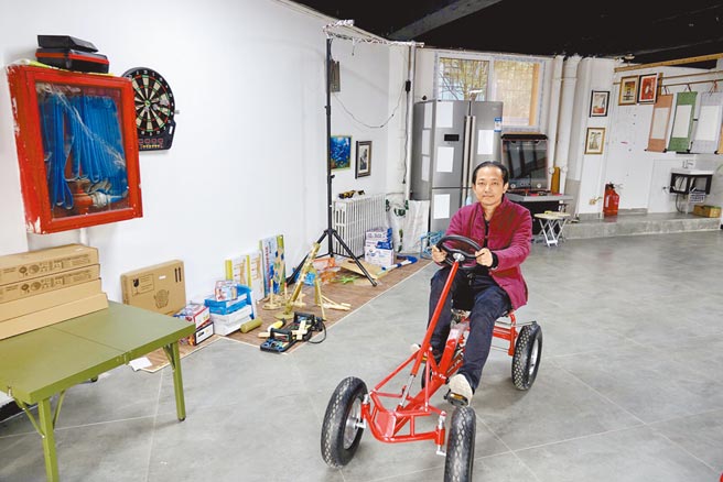 老年玩具店创办人宋德龙，骑着店内的四轮脚踏车，笑称这是古代的「卡丁车」。（摘自新京报）