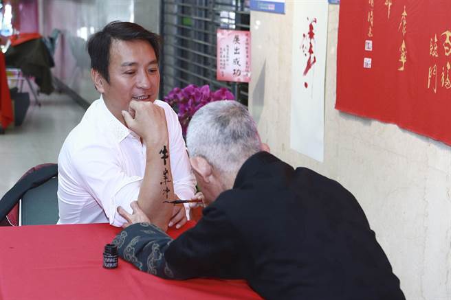 黄明胜老师在王中平手臂上挥毫。（民视提供）