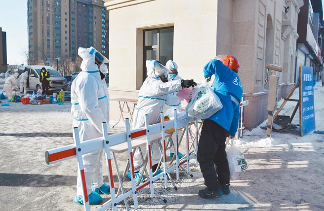 圖為防疫工作人員為隔離居民運送生活物資。（中新社）