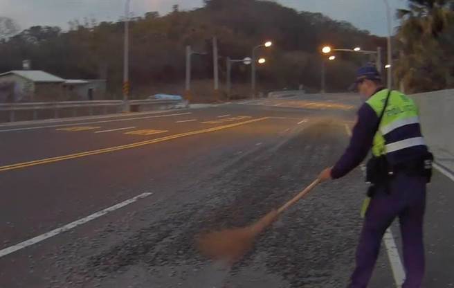 竹南警分局造橋分駐所所長呂文正清除路中掉落砂土。（竹南警分局提供／謝明俊苗栗傳真）