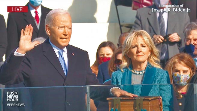 拜登就任美国总统典礼20日在华府国会山庄登场，拜登手按圣经宣誓就职。（摘自PBS直播）