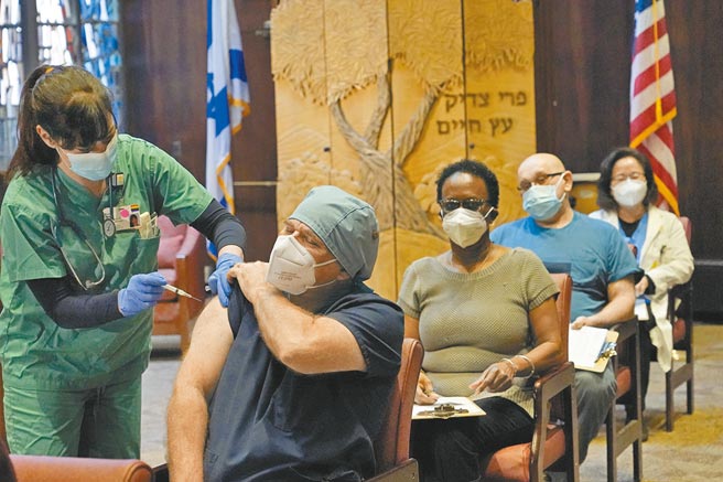 美国波士顿护理人员崔伯（前），戴口罩注射新冠疫苗。新任总统拜登预期，美国恐有60万人死于新冠病毒。（美联社）