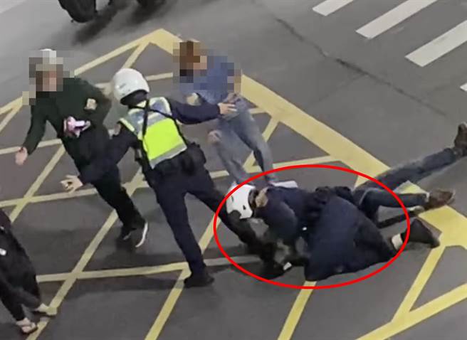 新北市三重区24日凌晨有民眾酒醉闹事，警方到场处理还遇上家属欲制止执法，场面相当混乱；红圈处为警方将醉汉压制在地，还可见另位警察在一旁拦着家属。（脸书社团《爆料公社二社》／苏育宣翻摄）