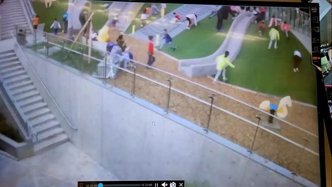 蓝色衣服的男童从坡道奔跑下来，不慎跌倒额头撞上石椅。（新北市交通局提供）