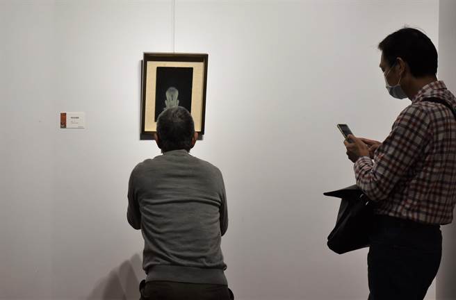 民眾对苏旺伸的作品《黑色助选员》很有感觉，拿起手机记录。（林瑞益摄）