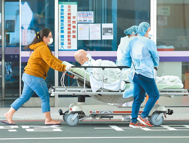 桃园医院全院被列入红区警戒，一名重症病患25日由医护人员推着病床自门诊中心转至急诊中心。（陈怡诚摄）