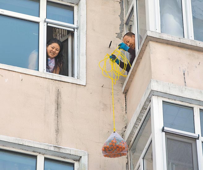 大陆吉林省通化市自发生聚集疫情，据最新通报，当地现有202例确诊，重灾区通化市日前已「封城」。图为黑龙江省绥化市北林区「居家令」延长一周    1月26日，在绥化市北林区一处居民楼，居民用绳子接收配送的生活物资。（新华社）