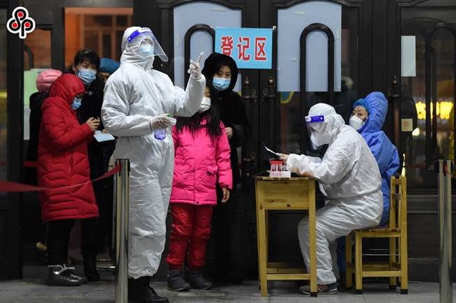 陆媒《环球时报》社评指中国需要成为接种疫苗最快的国家。图为1月22日，在哈尔滨市奋斗小学核酸检测点，医务人员为市民登记身分资讯。（新华社）