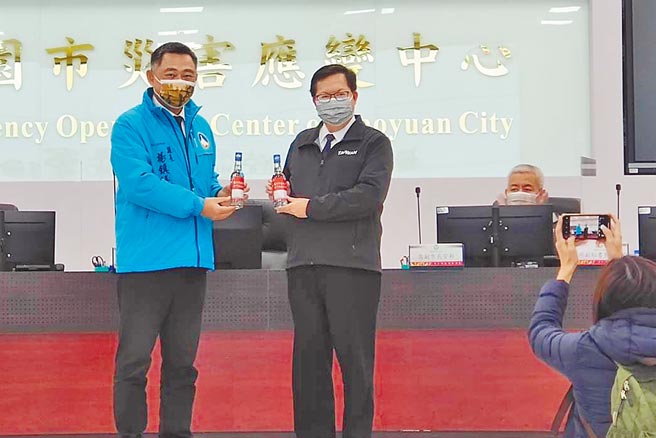 金门县长杨镇浯（左）27日致赠酒精给桃园市长郑文灿（右）时表示，金门小三通也如同国门一般，对于桃园身为国门之都的压力，非常能感同身受。（赖佑维摄）
