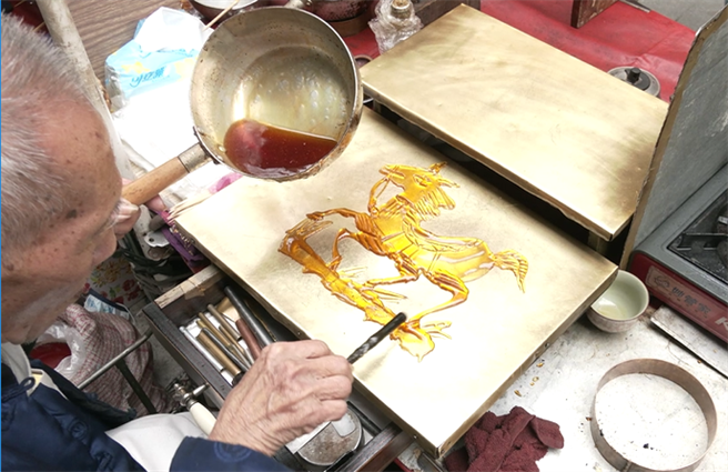 吴富雄的爸爸也是画糖师傅，他从小就跟在爸爸身边，一边看着他画糖表演，一边帮忙做简单的煮糖工作。(摄影/邱子轩)