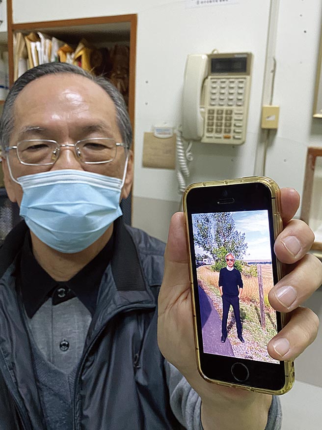 黄重彦拿起手机，秀出哥哥黄芳彦的生活照。（冯惠宜摄）