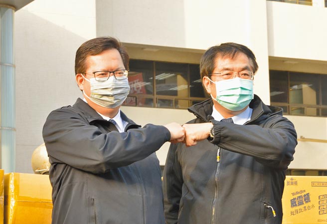 台南市长黄伟哲（右）29日到桃园捐赠物资，感谢桃园守住国门之都，和桃园市长郑文灿（左）击拳。（赖佑维摄）