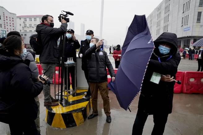 世衛組織專家組進入武漢華南海鮮市場訪問，大陸的工作人員以雨傘阻擋隨行媒體攝影。（圖／美聯社）