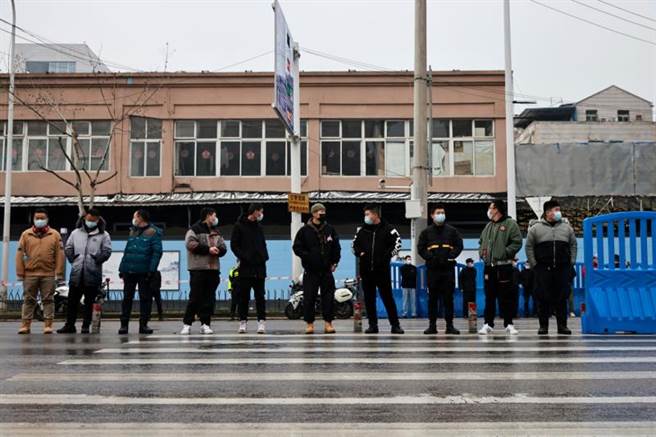 世衛專家進入武漢海鮮市場後，大批著便裝的安全人員排成一排阻止任何人靠近市場與專家組成員。（圖／路透）