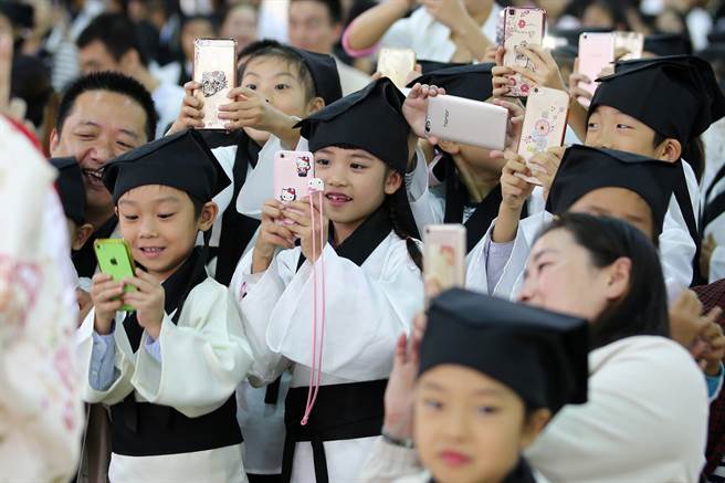青少年过度使用手机的情况愈来愈严重，除影响视力健康之外，也影响学校正常教学活动。图为南京市小学生身着汉服的孩子们用手机在相互拍摄。（图／中新社）