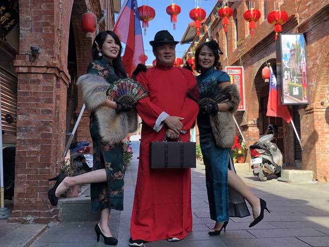 金城镇长李诚智下午偕2名穿着旗袍的女子，在繁复拱圈的映衬下，穿越人来人往的模范街直街，亲自为「后浦小镇春节游」打广告。（李金生摄）