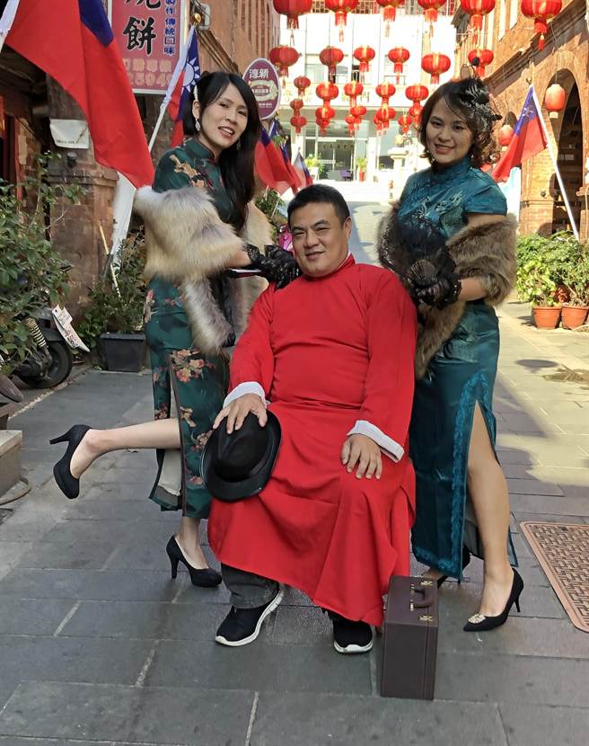 金城镇长李诚智下午偕2名穿着旗袍的女子，在繁复拱圈的映衬下，穿越人来人往的模范街直街，亲自为「后浦小镇春节游」打广告。（李金生摄）