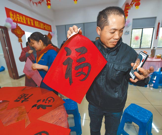 浙江省湖州市吴兴区东林镇一家纺织企业的员工通过手机视讯与家乡亲人分享企业的迎新春活动。（新华社）