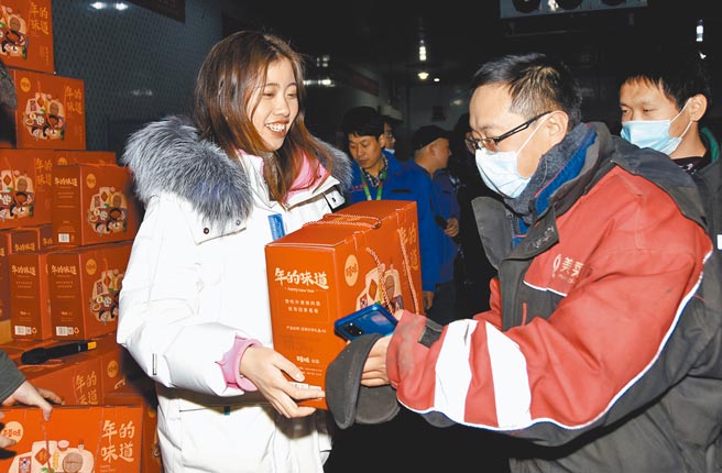 大陆各地台商纷纷以礼品、奖金，鼓励员工就地过年。图为企业「就地过年」的员工（右）在领取春节慰问品。（新华社）