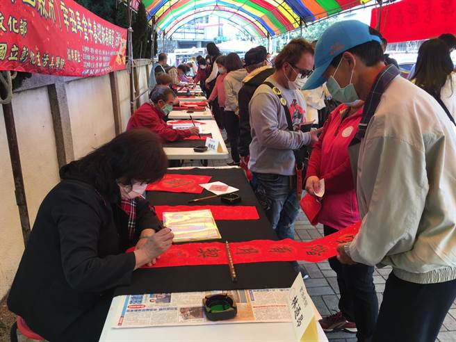 台中市议长张清照服务处举办挥毫送春联活动，民眾戴口罩、保持安全距离，排队领取。（王文吉摄）