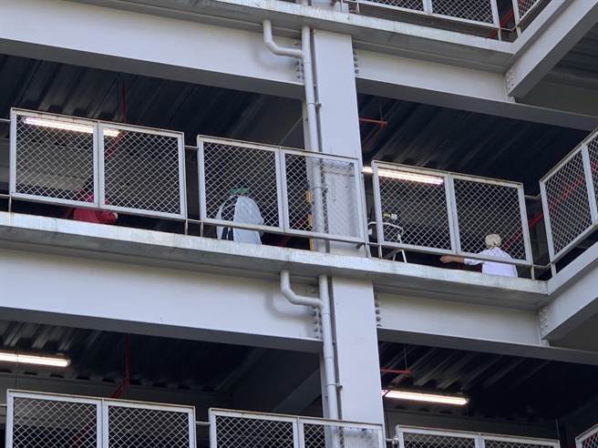 桃醫立體停車場後方可見醫護人員身穿防護衣、防護帽協助採檢作業。（姜霏攝）