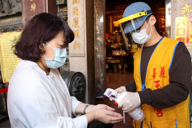 嘉义市长黄敏惠（左）由戴透明面罩防疫的玉皇宫工作人员喷酒精消毒手部。（廖素慧摄）