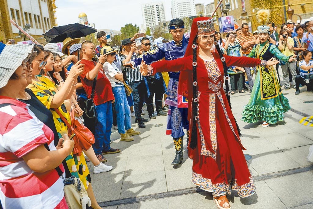 新華社發長文駁斥外國媒體對新疆的報導，列出24項謊言。圖為遊客圍觀新疆烏魯木齊市的表演者跳舞。（中新社）