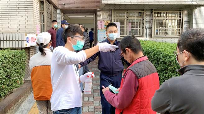 民眾排隊投票，選務人員量測體溫、噴酒精。（柯宗緯攝）