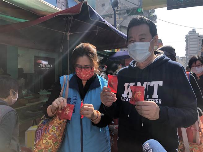 国民党团总召费鸿泰上午偕同太太王怡心，一同到吴兴市场向民眾拜早年，沿路发放春联、印有发财字样的饼乾。（赵婉淳摄）