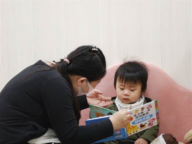 嘉義市公共托嬰中心托育人員陪伴幼兒看兒童繪本。（廖素慧攝）