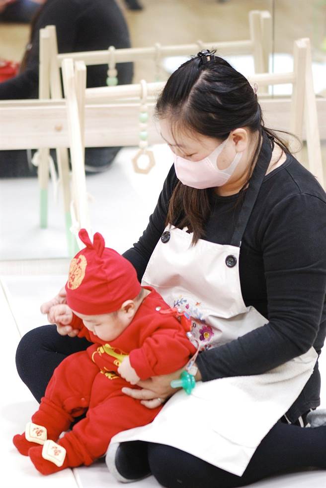 嘉義市公共托嬰中心托育人員陪伴幼兒看兒童繪本。（廖素慧攝）