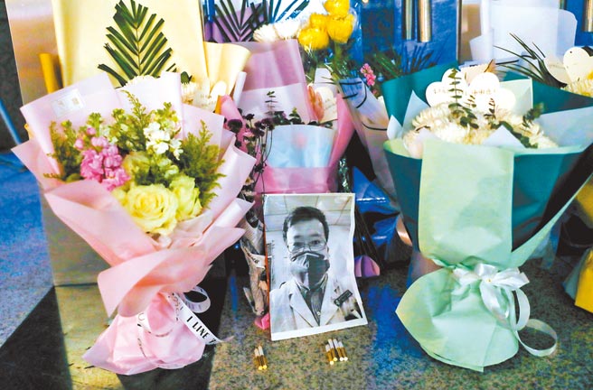 李文亮医师逝世周年，许多大陆民眾在网路上悼念。图为2020年2月7日李文亮过世后，武汉中心医院门口，摆放着他的黑白照片和祭奠鲜花。（中新社）