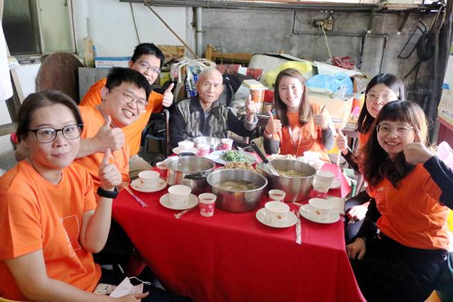 弘道基金会志工将桌子搬到前庭，布置红桌布端上热腾腾年菜，为杨伯伯生活的空间带来喜气与温暖。（卢金足摄）
